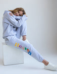 Person with 'Heaven' printed on the pants, sitting on a white box against a plain background.