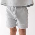 Gray shorts with 'Elevated Faith' text worn by a person on a white background