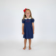 Young girl in a navy pleated dress with short puff sleeves and peter pan collar