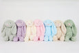 A lineup of 16 inch plush bunny toys in various pastel colors including pink, blue, purple, cream, grey, tan, and green.